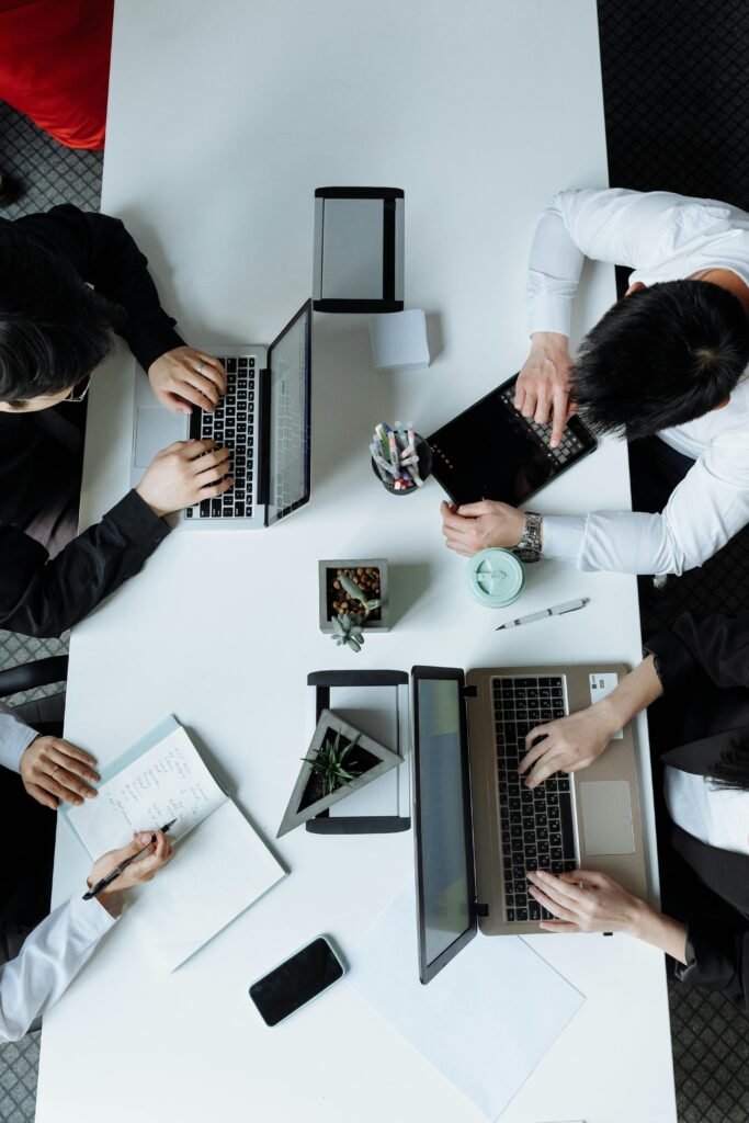 A diverse team working together in a modern office setting, focusing on laptops and collaboration.